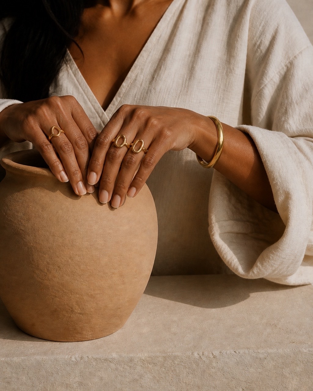 Hands and jewellery styled against an ivory sleeve.