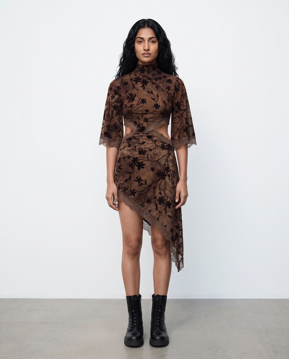 A full-length frame with the hem and the sheer sleeves reading against a soft studio wall.