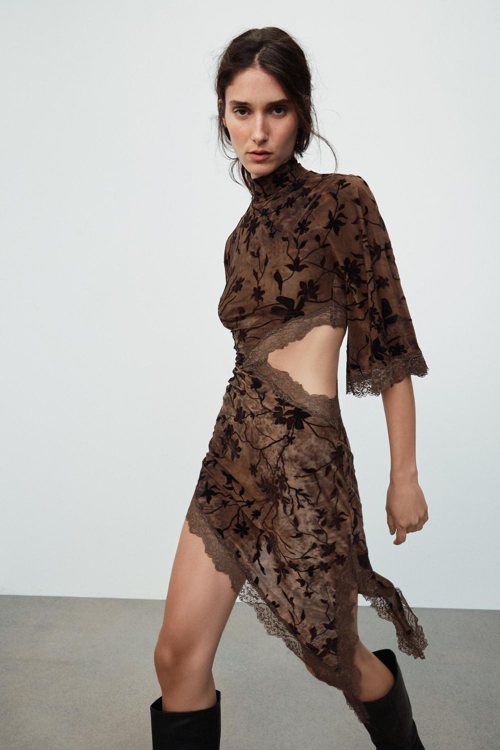 A brown floral mesh dress with an asymmetric hem, shot plainly on a model.