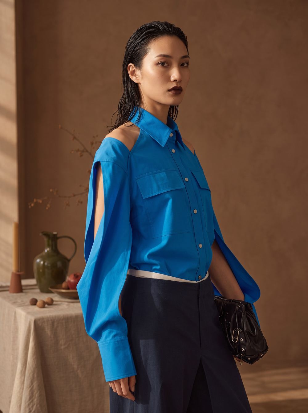 Three-quarter frame of the blue slit-sleeve shirt and navy trousers.