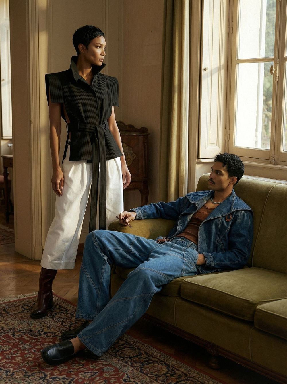 Two models in a period drawing room, one in the black vest and white skirt, one in denim.