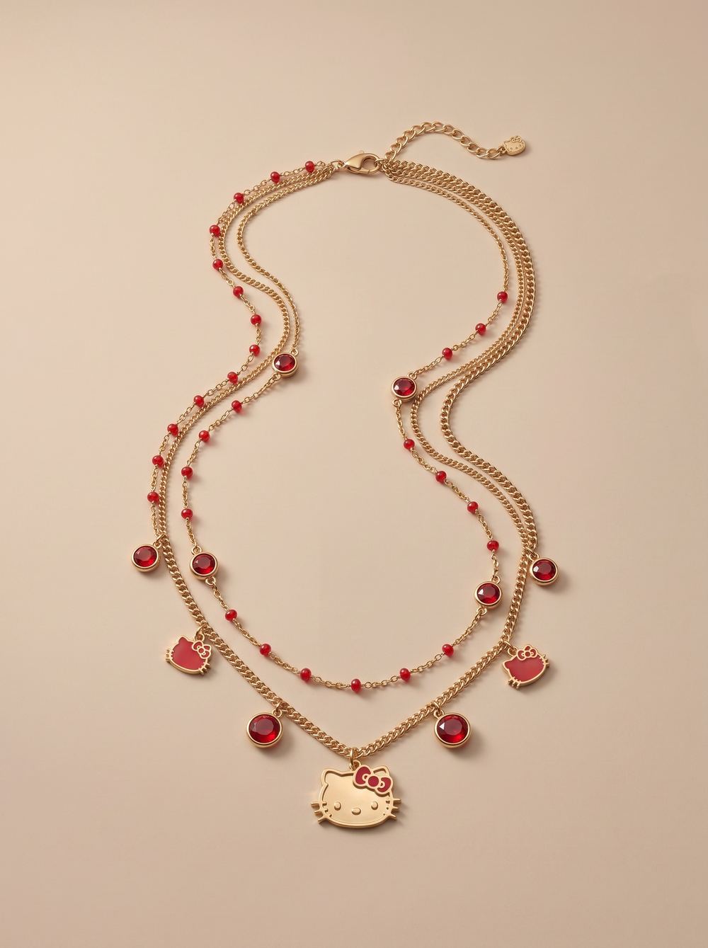 Gold charm necklace strung with red beads and an enamel character pendant.
